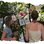 Participantes d'un atelier qui regardent leurs œuvres sécher dans un jardin