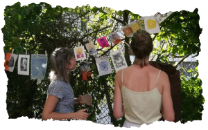Participantes d'un atelier qui regardent leurs œuvres sécher dans un jardin